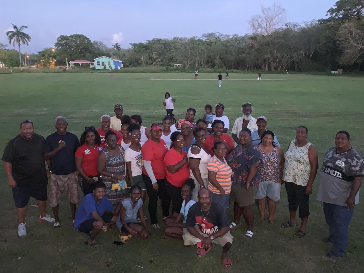Community meeting at Flowers Bank Village, Belize, with residents gathered on the village field at dusk